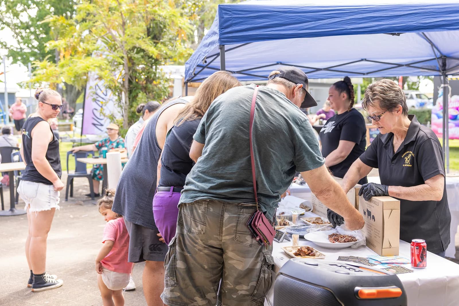 Visitors and event workers gathered at an outdoor market stand